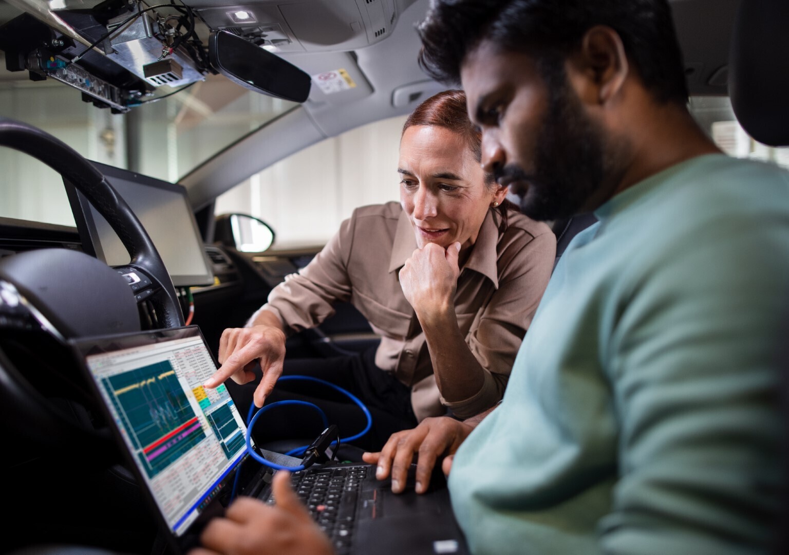 Engineers looking at a laptop inside of a car