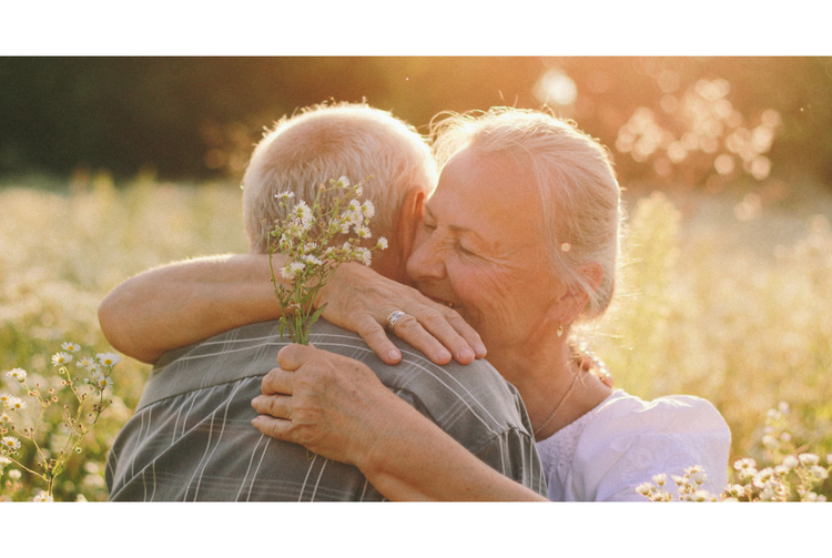 Two elderlies hugging each other in a corn field.