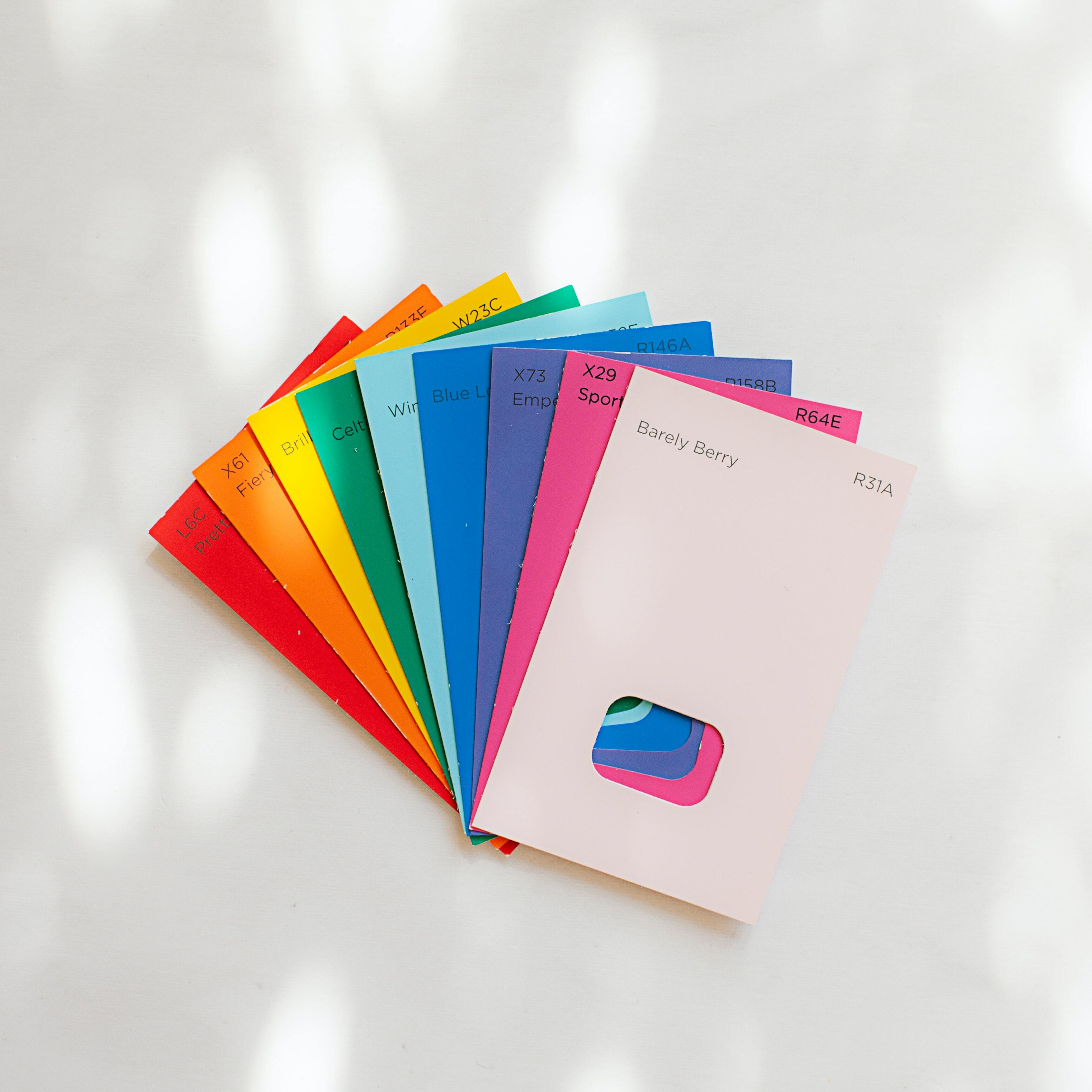 Bright, multicolored paint cards are arranged in the shape of a hand fan on a white background.