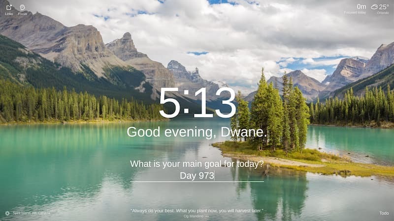 The photo shows a beautiful mountain landscape with a lake in the foreground. The water is a crystal-clear blue-green color, and the sky is a deep blue with hazy clouds. The mountains in the background are snow-capped, and the trees are a lush green. There is a small island in the lake with several trees on it. The island is located in the middle of the lake and is surrounded by water. The sky is clear with a few clouds. The photo was taken from the shore of the lake, and there are no people in the photo. The location is Spirit Island, AB, Canada.