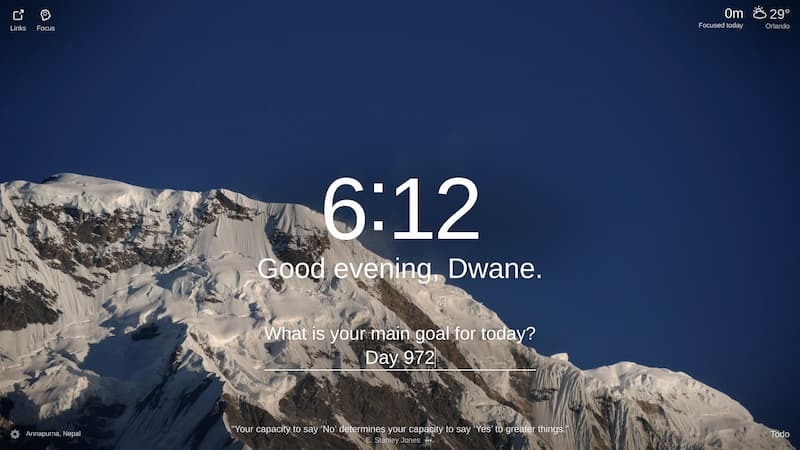 A photo of a snow-capped mountain with a blue sky in the background. The mountain is in the distance and appears to be very tall. The sky is clear and there are no clouds. The photo was taken from a low angle, making the mountain appear even more imposing. The mountain is Annapurna I, located in the Annapurna mountain range in Nepal.