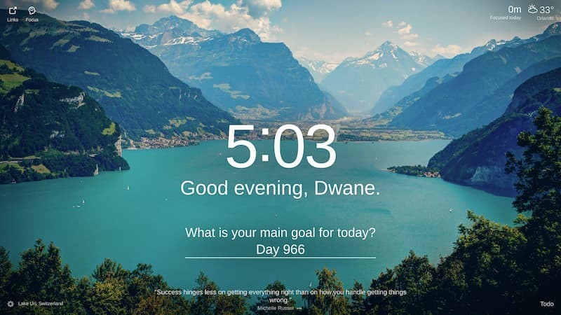 The photo shows a serene view of Lake Uri in Switzerland. The sky is clear, and the sun is shining. The lake is surrounded by snow-cappedcapped mountains, and there are lush green trees on the shoreline. There are a few boats on the lake. The photo is taken from a high angle, and mountains. There are a few trees on the shore. The water is a teal color. There are a few boats on the lake. There are some houses it provides a stunning view of the surrounding landscape. on the shore. The photo is taken from a high angle.