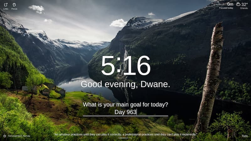  The photo shows a view of Geirangerfjord, Norway. The fjord is surrounded by steep mountains and cliffs, and there is a small village nestled on the shore. The water is calm and still, and the sky is clear. The overall effect is one of peace and tranquility.