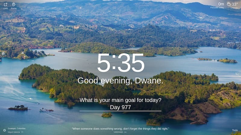 The image is of a beautiful landscape of Guatapé, Colombia. The sky is clear and blue, and the sun is shining brightly. The image is very peaceful and relaxing. There is a large lake, surrounded by lush green hills. There are several small islands in the lake, and the shores are dotted with trees. In the background, there is a majestic mountain range, with snow-capped peaks. The water in the lake is crystal clear. The sky is a deep blue color, and the sun is shining brightly.