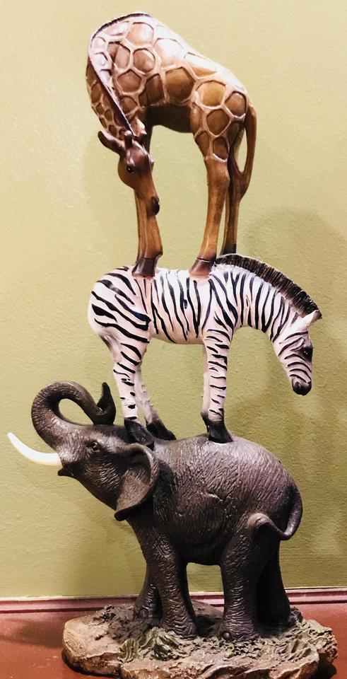 A small statue of a giraffe standing on a zebra which in turn is standing on an elephant